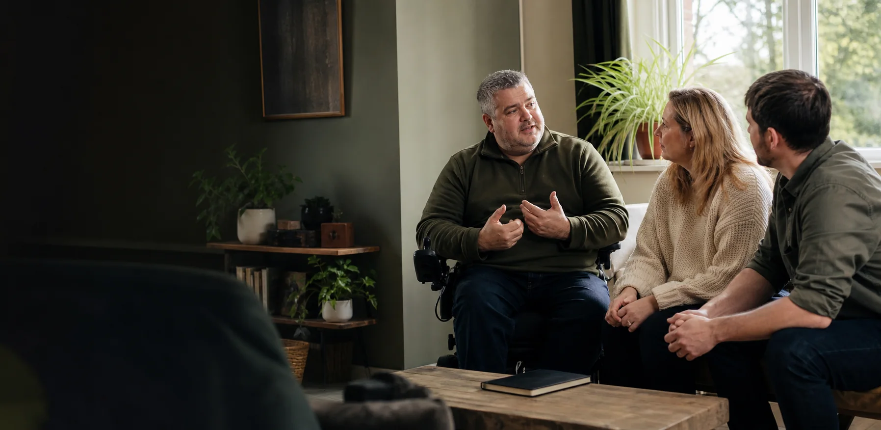 A disabled man leading a care-planning conversation in his own home