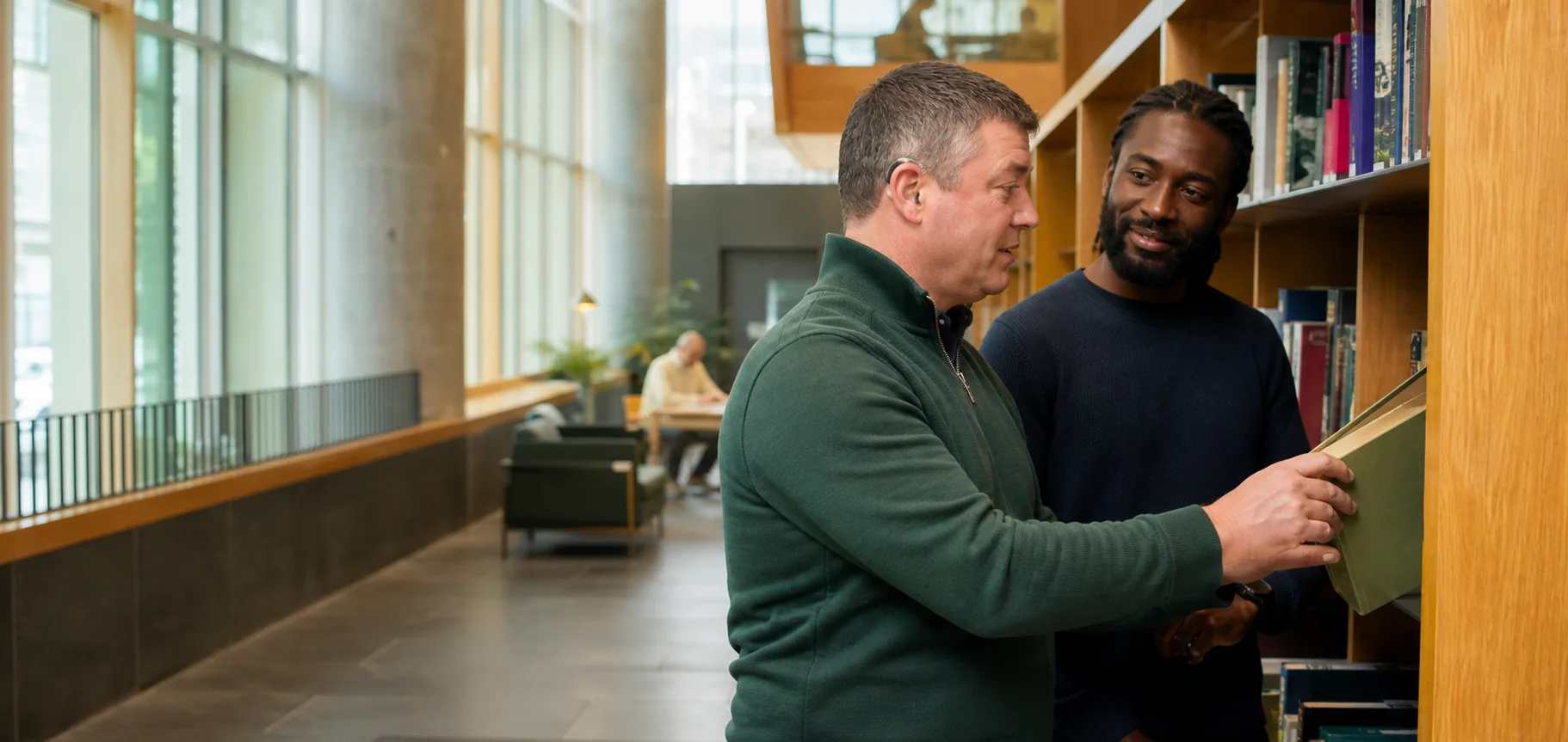Two men choosing a book together in a bright community library