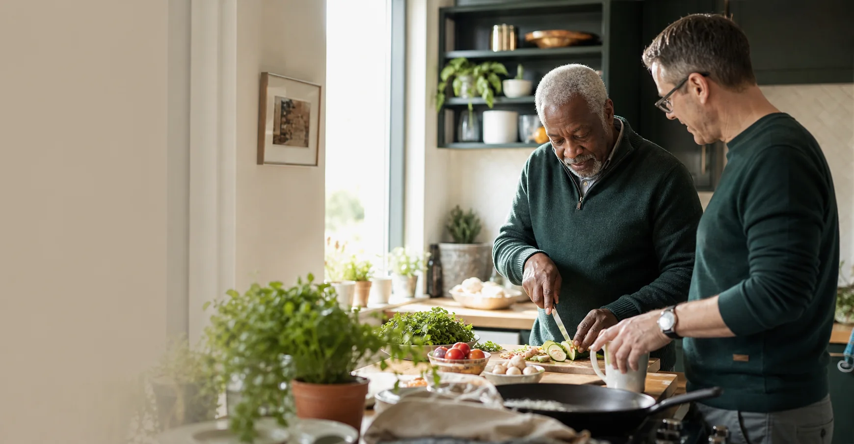 An older man preparing a meal at home with practical support from a companion